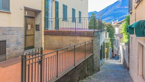 Un escalier étroit en pierre menant à un bâtiment doté d’une rambarde en métal.
