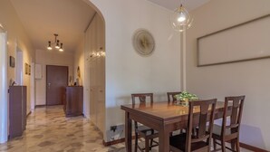 Un coin repas avec une table et des chaises en bois, un luminaire suspendu et un objet décoratif fixé au mur.