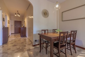 Un coin repas avec une table et des chaises en bois, un luminaire suspendu et un objet décoratif fixé au mur.