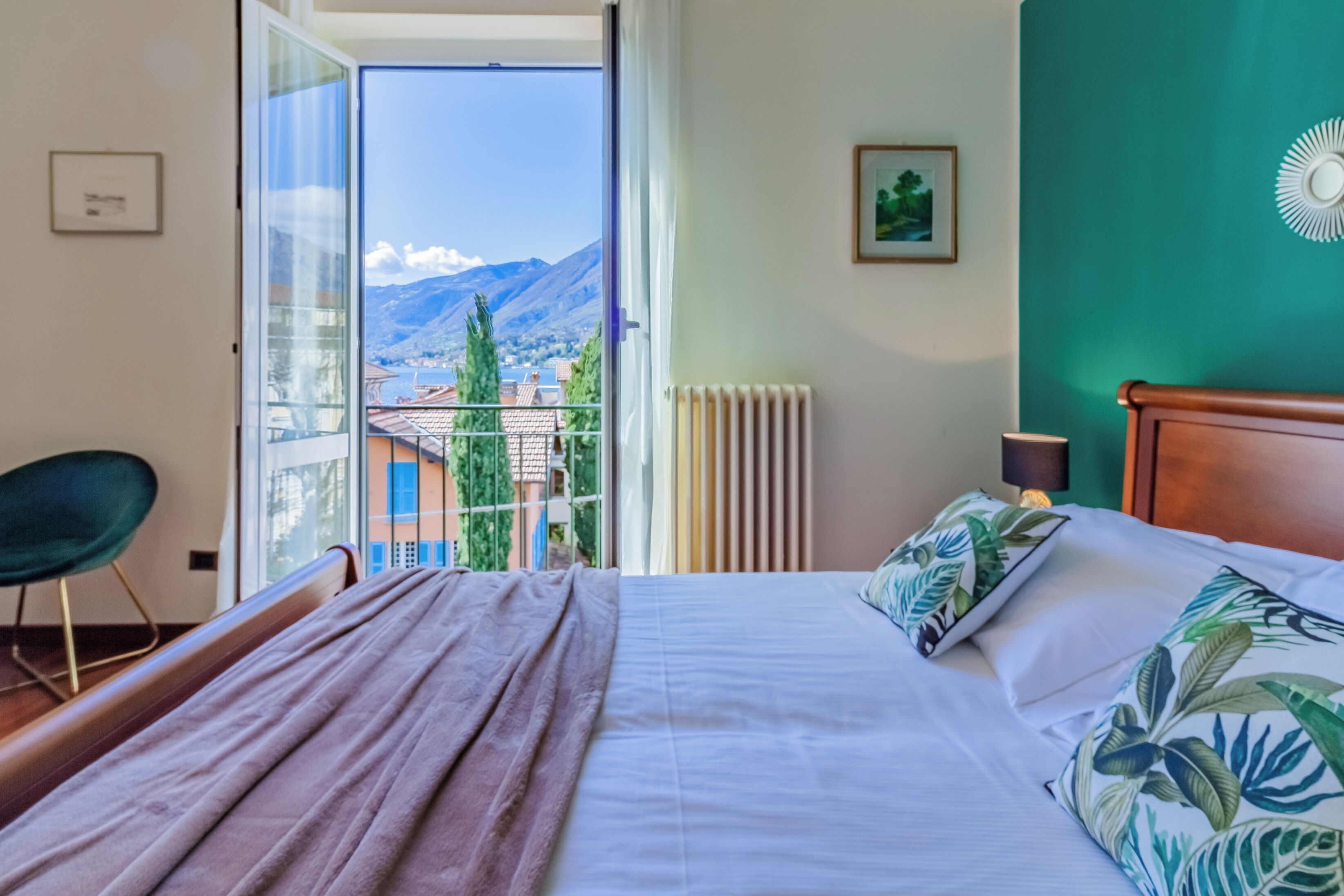 Una camera da letto con un letto grande, vista sulle montagne, una sedia e un termosifone.