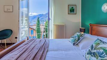 Una camera da letto con un letto grande, vista sulle montagne, una sedia e un termosifone.