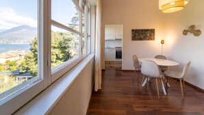 Une pièce dotée d’une grande fenêtre, d’une table à manger avec des chaises, d’un coin cuisine et d’un luminaire suspendu.