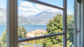 Vista a través de una ventana de una zona costera con montañas, un lago y edificios.