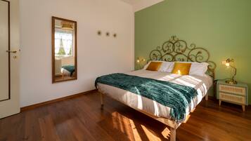 Un dormitorio con cama, mesita de noche, lámpara, espejo y puerta.
