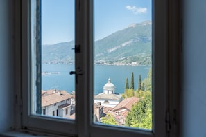 A window view of a lake with buildings and a mountain in the background.