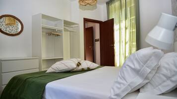 Un dormitorio ordenado con cama, armario y lámpara de noche.