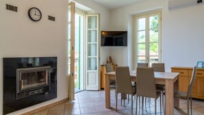 Un coin repas avec une table et des chaises en bois, une cheminée et un téléviseur fixé au mur.