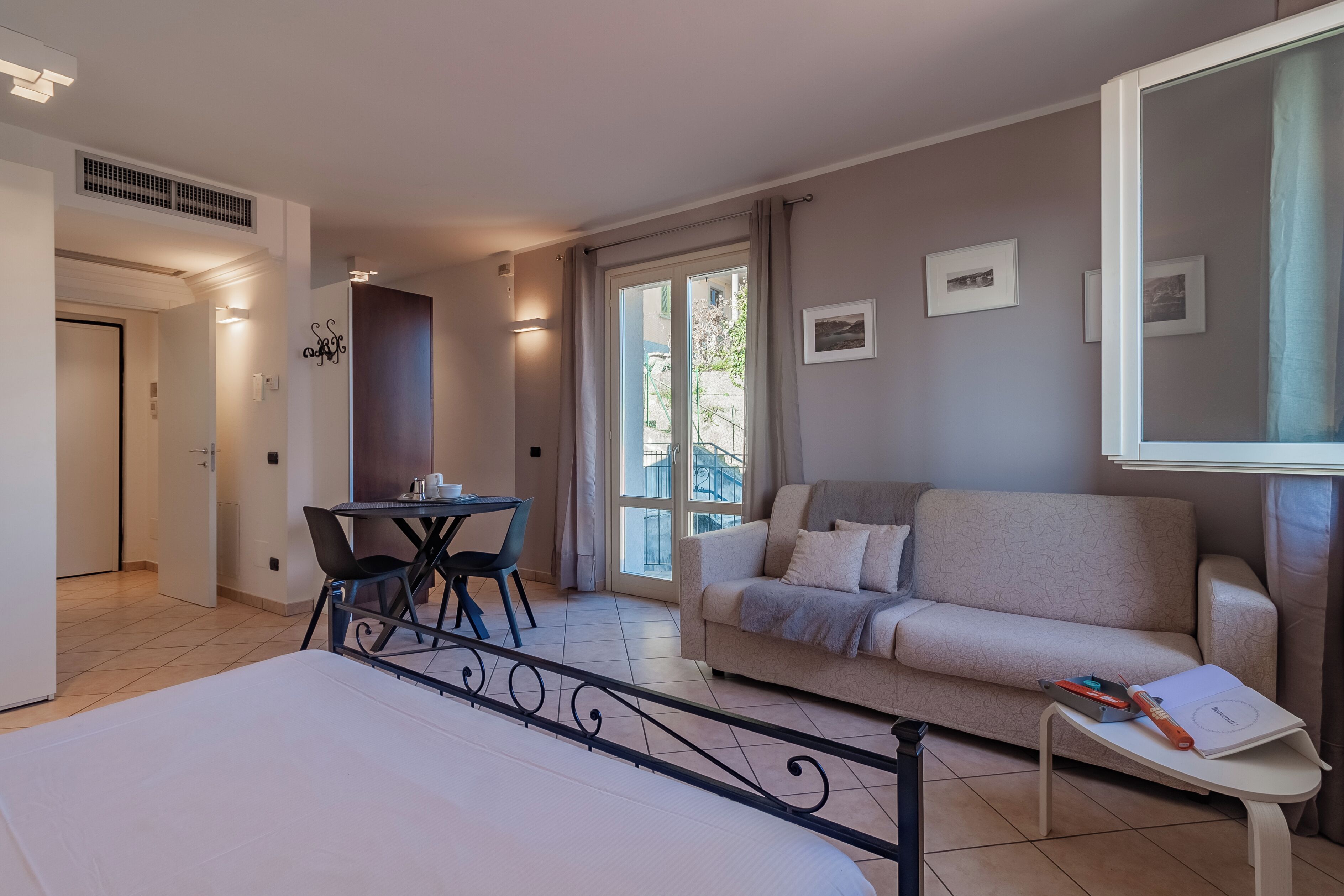 Habitació d'hotel moderna amb llit, sofà, taula petita i un balcó amb vistes.