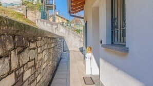 A narrow stone pathway leading to a building with a white facade and a window with metal bars. - Incanto Apartment - One Bedroom Apartment, Sleeps 2 (Bellagio)