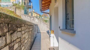 Un estrecho sendero de piedra que lleva a un edificio con fachada blanca y una ventana con rejas.