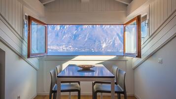 Un comedor con mesa y sillas, una ventana que ofrece vistas a un paisaje urbano y un techo de madera.