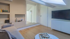 Ein modernes Wohnzimmer mit Dachfenster, einem Flachbildfernseher, einer Couch und einem Couchtisch mit einem Schachspiel.
