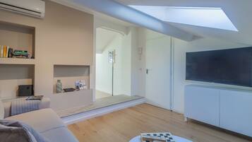 Una sala de estar moderna con tragaluz, un televisor de pantalla plana, un sofá y una mesa de centro con un juego de ajedrez.