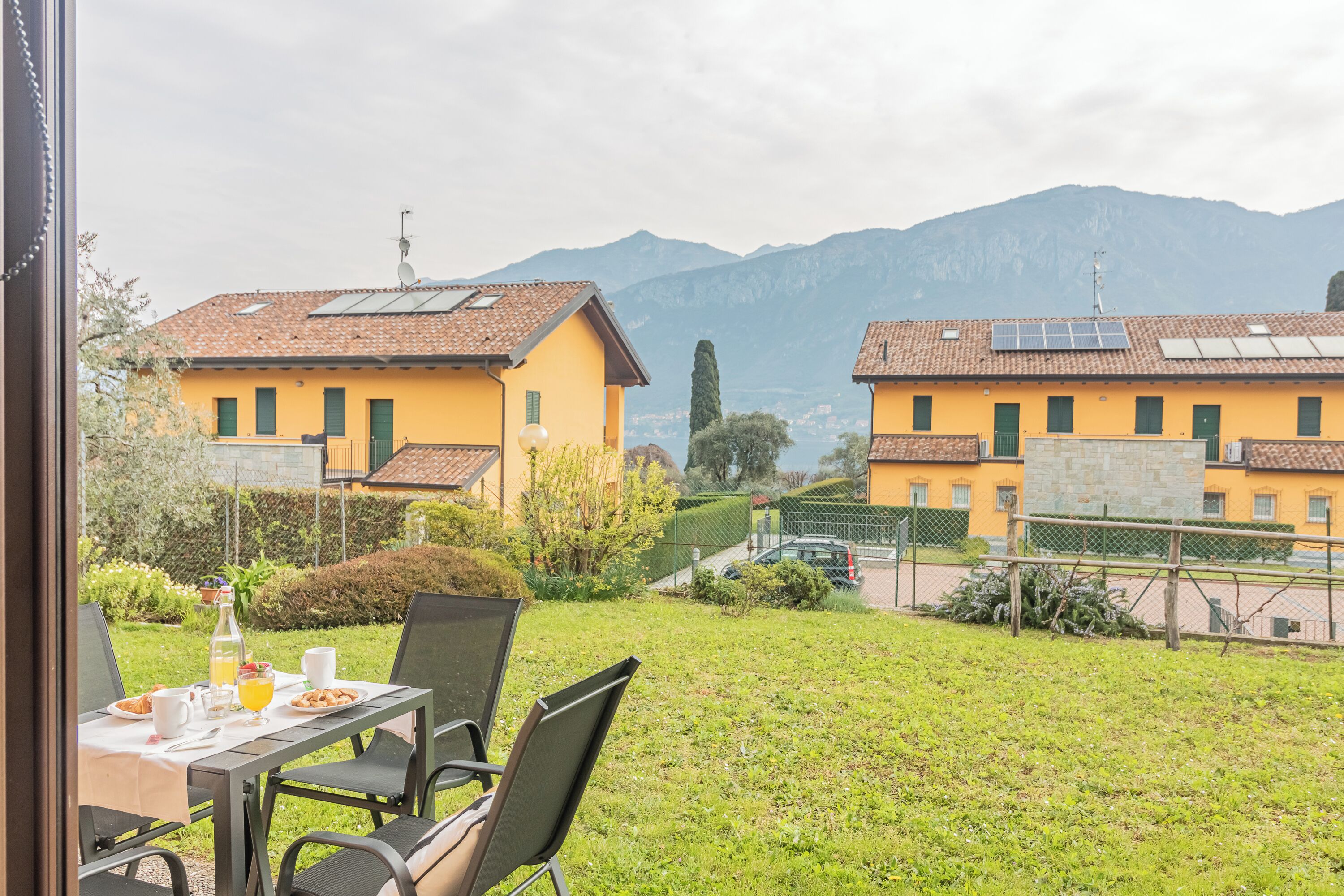 Ein Essbereich mit Tisch für zwei Personen, mit Blick auf einen Innenhof und einen Berg im Hintergrund.