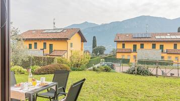 Ein Essbereich mit Tisch für zwei Personen, mit Blick auf einen Innenhof und einen Berg im Hintergrund.