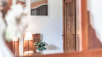 Ein Zimmer mit Holztür, Wandspiegel, Lampe und einer Topfpflanze.