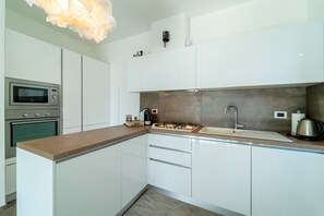 A modern kitchen with white cabinets, a built-in oven, a microwave, a gas stove, and a sink. - Ritzy Ka'Doro Lakeview (Nesso)