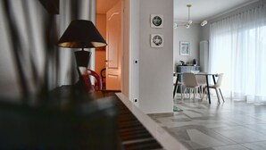 Ein modernes Wohnzimmer mit einem Klavier, einem Essbereich und einer Küche im Hintergrund.