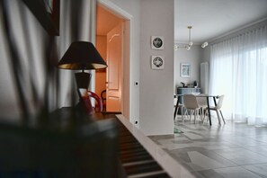 Un salon moderne avec un piano, un coin repas et une cuisine en arrière-plan.