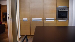 Una cocina con armarios de madera, horno empotrado y una mesa de comedor.