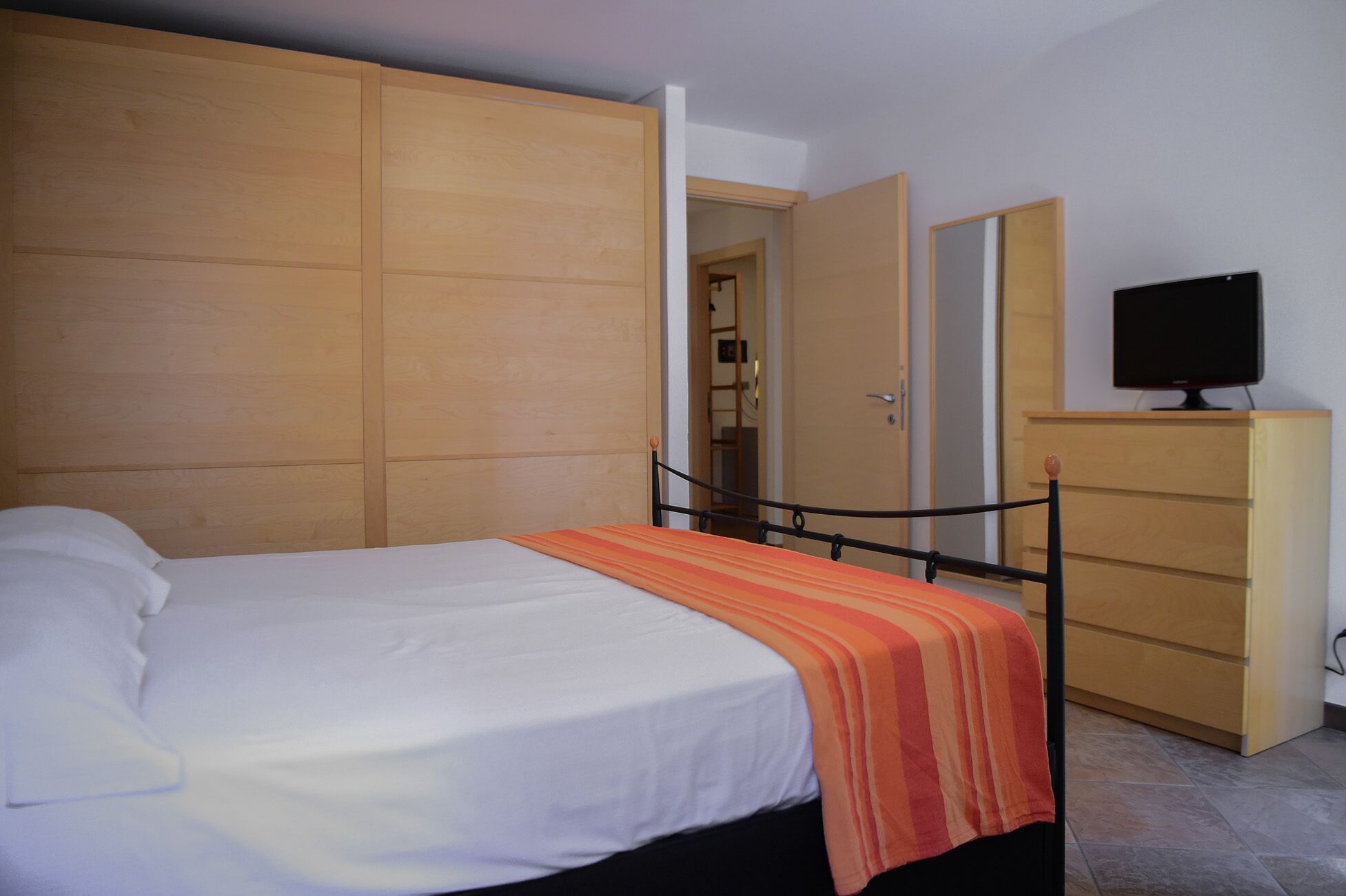 A bedroom with a bed, a dresser, and a television.