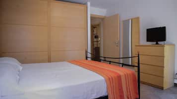 A bedroom with a bed, a dresser, and a television.
