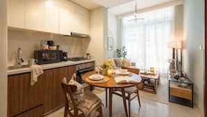 A modern kitchen with a dining area, a sofa, and a lamp. - Elegant Reva 1BR - Pool & Gym (Dubai)