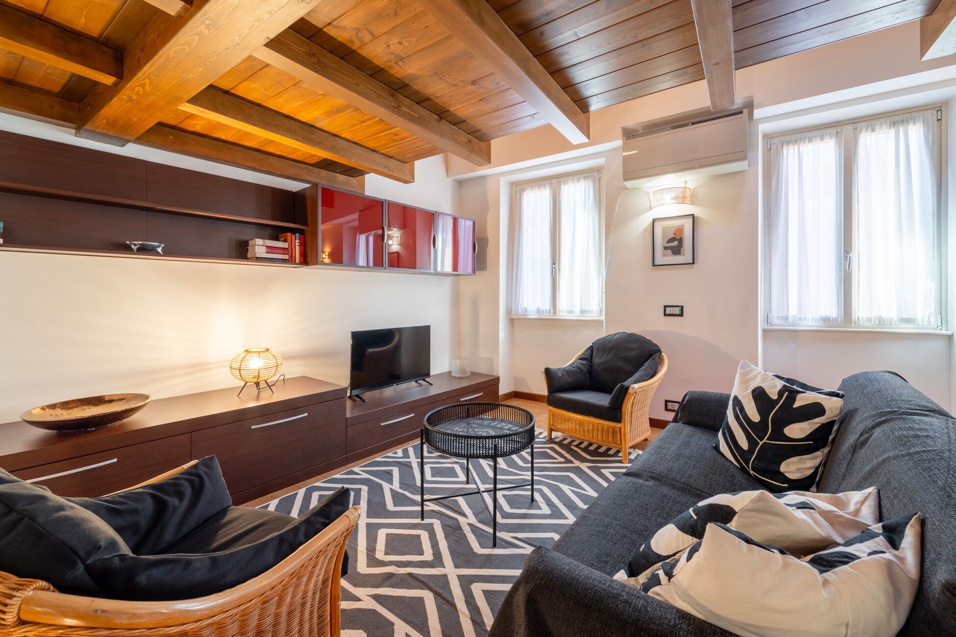 Una sala de estar moderna con televisor, sofá, sillones y un tapete estampado.