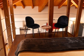 A balcony with two black chairs, a small round table, and a bed. - Roncati Loft Apartment (Bellagio)
