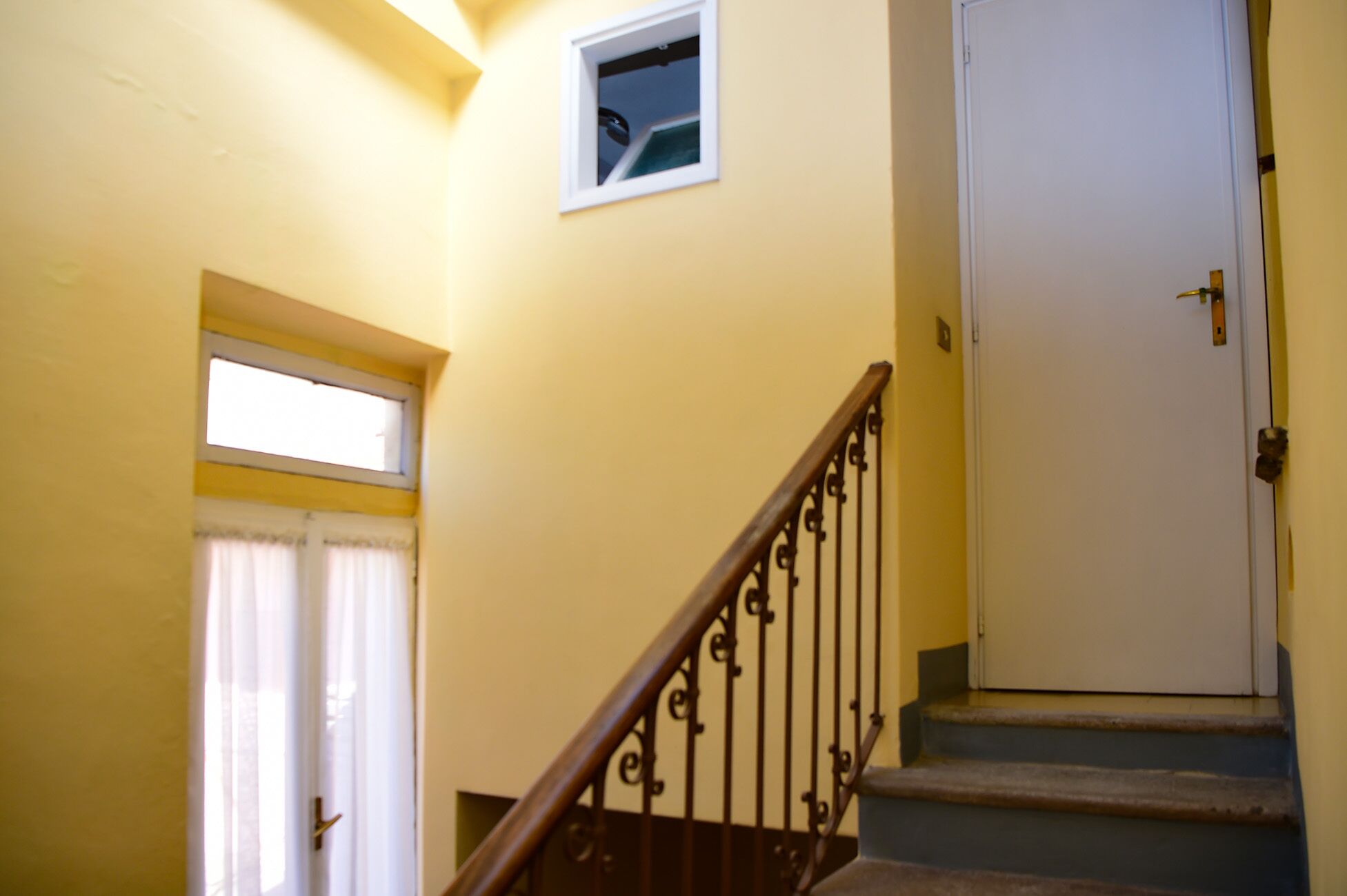 Una escalera con barandilla de madera y una puerta blanca al final.