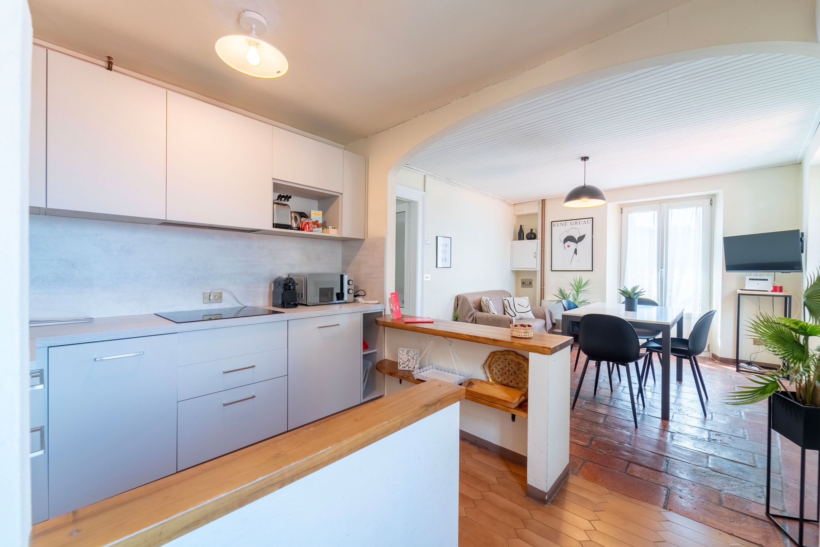 Una cocina moderna con armarios blancos, encimera de madera y un comedor con mesa y sillas.