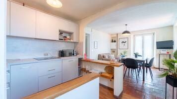 Una cocina moderna con armarios blancos, encimera de madera y un comedor con mesa y sillas.