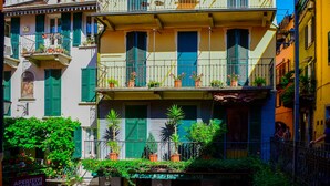 Un immeuble à plusieurs étages doté de balcons, de plantes en pot et d’une enseigne indiquant « Aperitivi Wine Bar ».