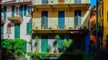Un edificio de varios pisos con balcones, plantas en macetas y un cartel que dice 'Aperitivi Wine Bar'.