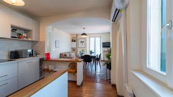 A modern kitchen with a wooden countertop, a dining area with a table and chairs, and a hallway leading to a living room.
