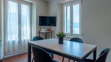 Un comedor con una mesa, sillas, un televisor y una planta.