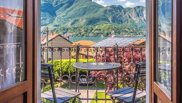 A balcony with a view of mountains, a table, and chairs.
