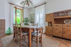 Un coin repas avec une table et des chaises en bois, un vase vert et un meuble avec des portes en verre.