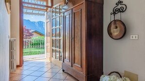 A room with a wooden cabinet, a wall-mounted clock, and a view of mountains through a glass door.