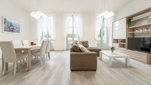 Ein modernes Wohnzimmer mit Sofa, Esstisch, Stühlen und Fernseher.