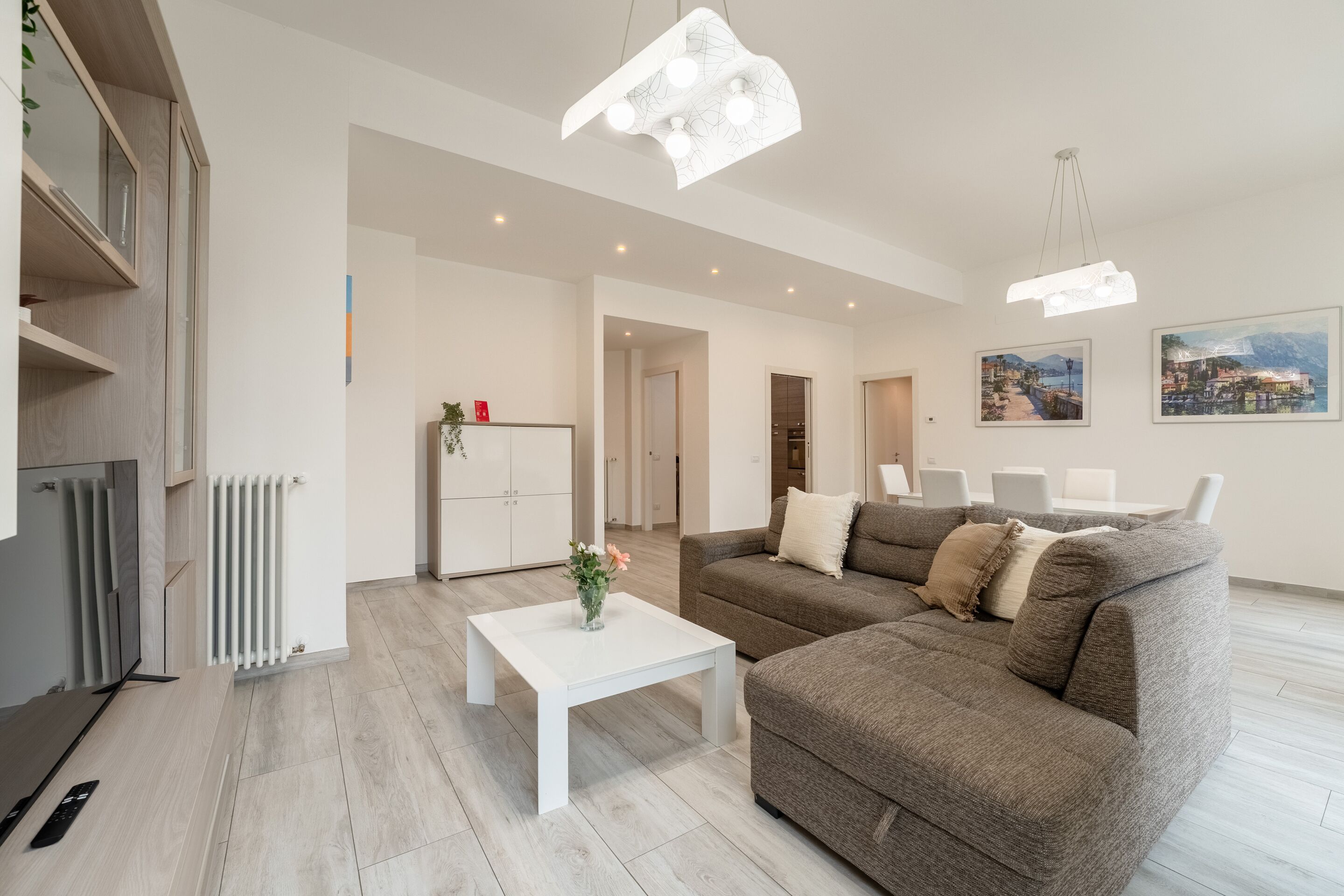 A modern living room with a white coffee table, a brown sofa, and a unique light fixture.