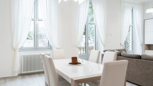 Ein modernes Wohnzimmer mit einem weißen Esstisch, weißen Stühlen und einem grauen Sofa.