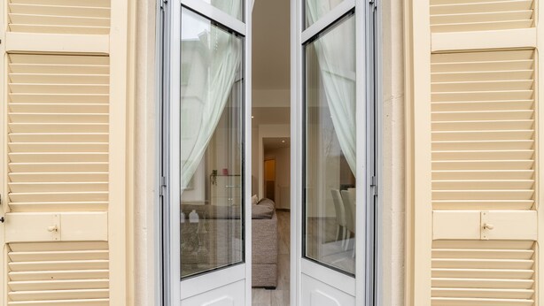 Ein Korridor mit beigen Fensterläden, einem Bett und einer Heizung.