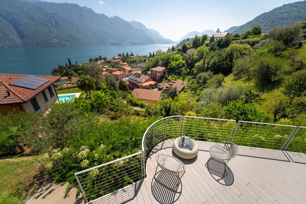 A terrace with outdoor furniture, overlooking a mountainous landscape with a lake and a village. - Zinnia Lakeview Apartment (Bellagio)