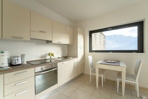 A modern kitchen with a dining area, featuring a window with a mountain view. - Zinnia Lakeview Apartment (Bellagio)