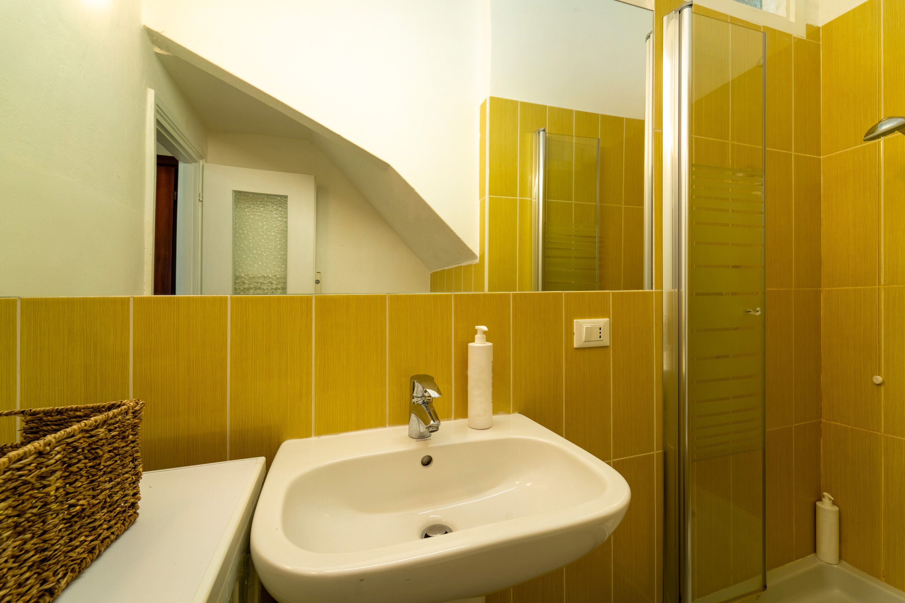 Une salle de bain avec un lavabo, une douche et des murs jaunes.