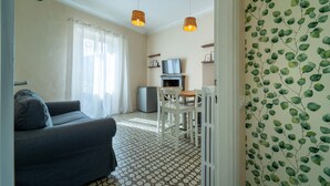 Un salon comprenant un canapé, une table à manger avec des chaises, un téléviseur et un petit réfrigérateur.