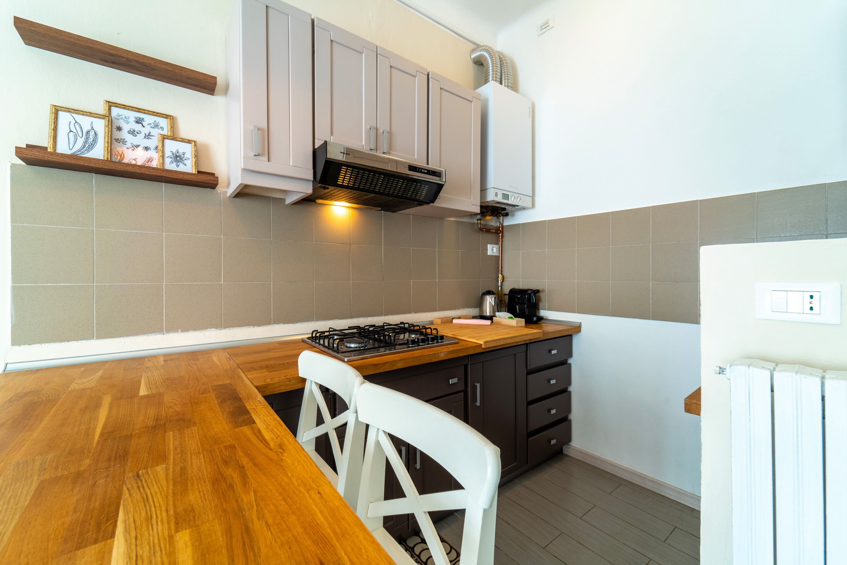 Una cocina con una mesa de madera, sillas blancas, una estufa a gas y armarios.
