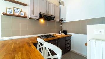 Una cocina con una mesa de madera, sillas blancas, una estufa a gas y armarios.