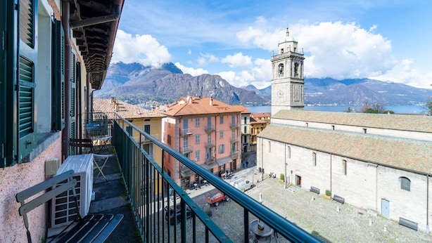 Un balcon donnant sur une place de ville, des bâtiments et une chaîne de montagnes.